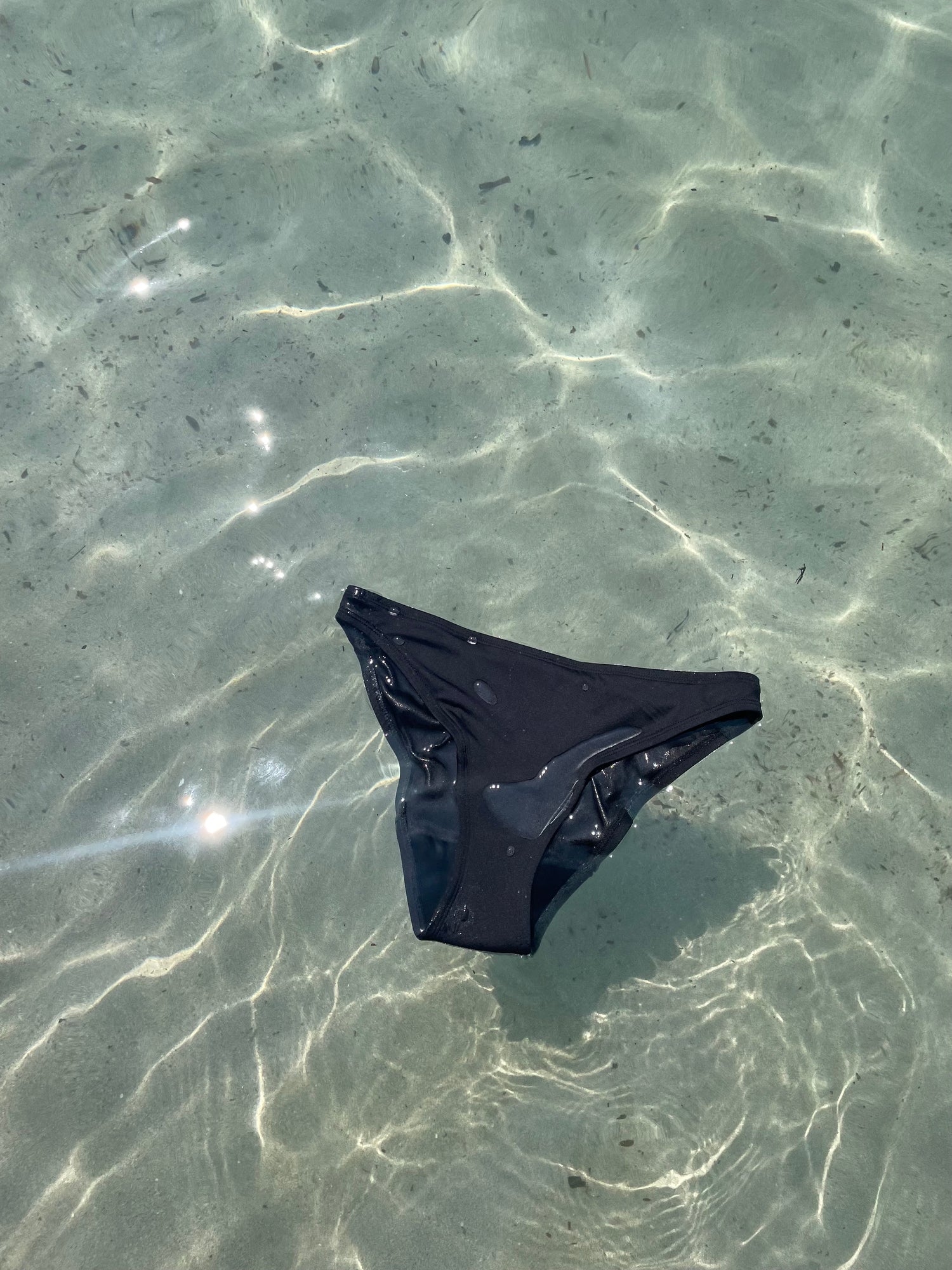 black POM period swimwear floating in the ocean